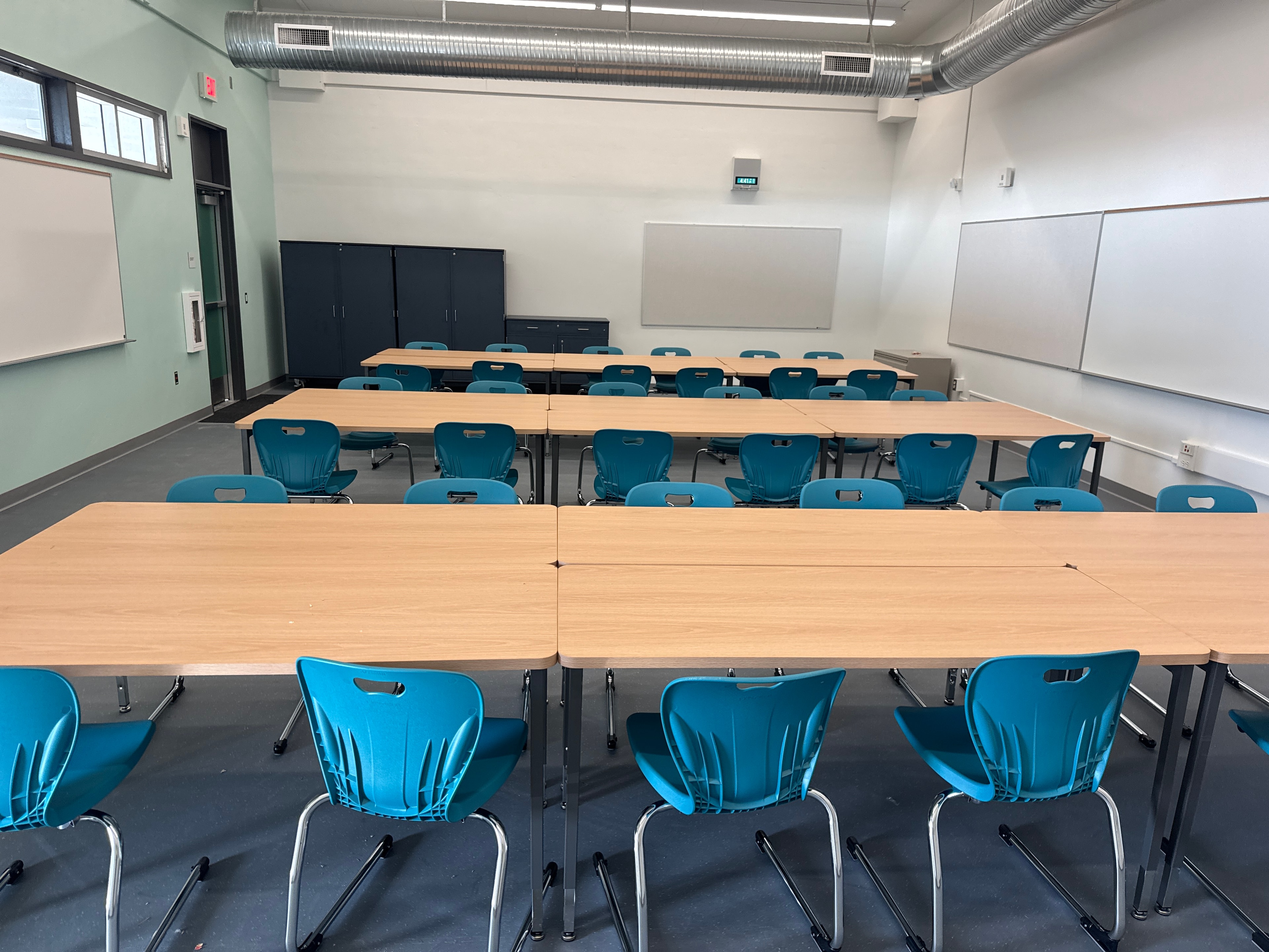 Completed classroom setup with teal chairs and wood tables