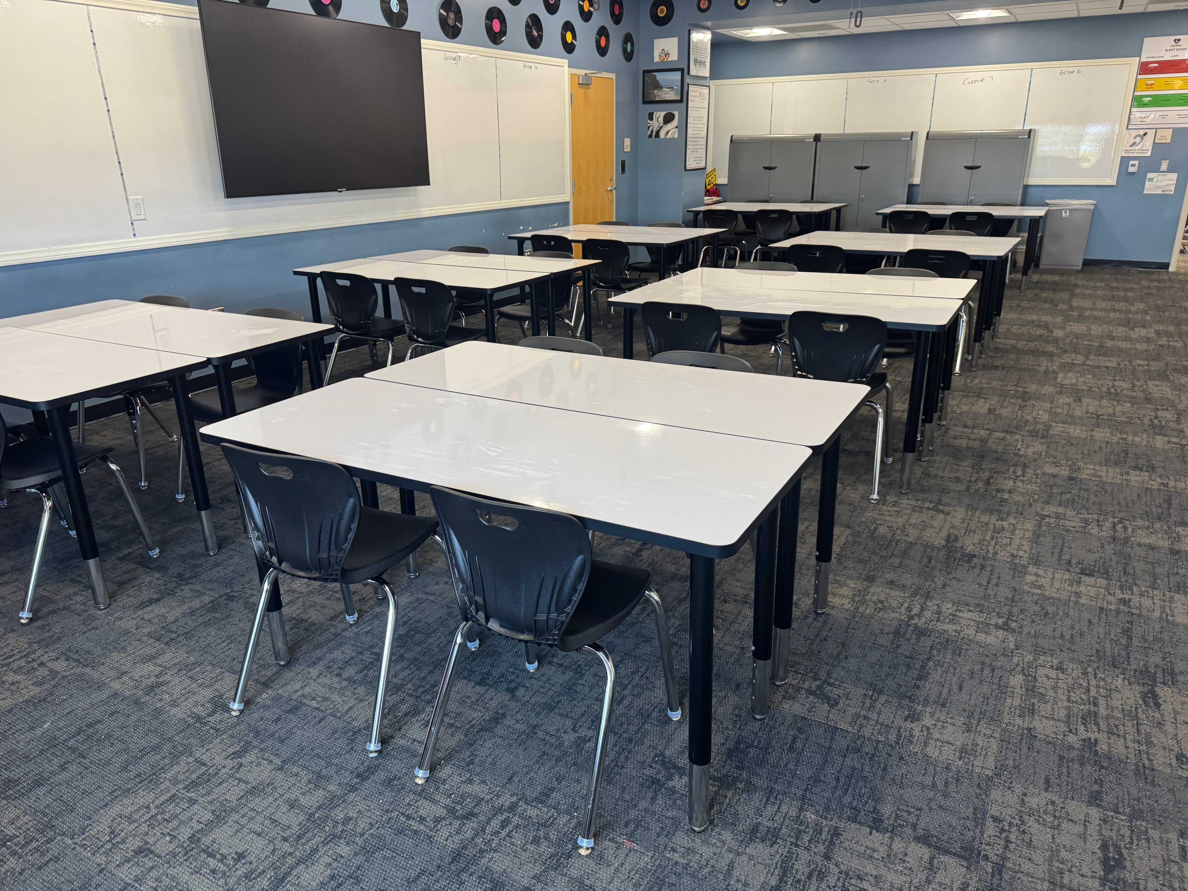 Classroom furniture installation — white desks and black chairs